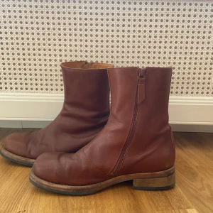 Bruna skinnboots Our legacy  - Säljer ett par klassiska bruna boots från Our legacy. Dem är i relativt bra skick, smörjning kan efterfrågas vid köp.