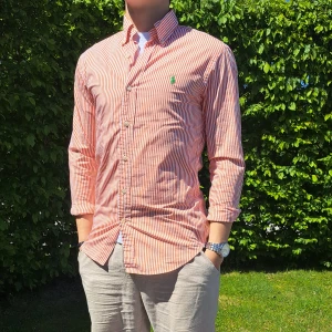 Randig Ralph Lauren skjorta- Stl S, Slim fit - Hej säljer en snygg Ralph Lauren skjorta I randigt mönster med färgerna orange och vit. Perfekt till sommaren! 🏝🏖 Skick: 9/10 utan defekter. Stl: S, Slim fit. Han på bilden är 170cm. 🤗