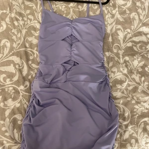 Ljuslila tight klänning - Säljer en ljuslila tight klänning med smala axelband och snygga rynkade detaljer framtill och längs sidorna. Klänningen har en figurnära passform och är perfekt för dig som vill sticka ut med en trendig look. Köpt utomlands