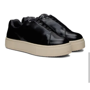 Eytys skor - Stilrena svarta sneakers med glansig finish och tjock beige platt sula. Skorna har snörning och en minimalistisk design som passar till många olika outfits. Använda några gånger💗