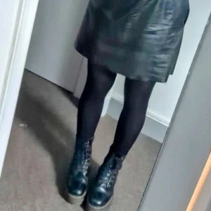 Svart kjol i skinnimitation från Sarah.Jo - Säljer en svart kjol i skinnimitation från Sarah.Jo. Kjolen har resår i midjan och en lätt utställd form som ger en snygg siluett. Perfekt att styla med boots eller sneakers för en cool look.