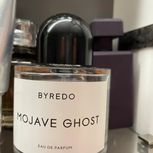 Byredo Mojave Ghost Eau de Parfum 100ml - Byredo Mojave Ghost är en exklusiv parfym med en stilren, transparent glasflaska och svart rund kork. Doften är inspirerad av Mojaveöknen och har en modern, minimalistisk design. Flaskan rymmer 100 ml och är tillverkad i Frankrike.