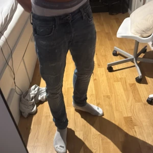Jack and Jones Blå slitna jeans med skinny fit - Säljer ett par blå jeans med skinny passform och slitna detaljer. Jeansen har flera hål och slitningar framtill och baktill, samt klassiska fem fickor. Perfekta för en avslappnad och trendig stil.M30 L32