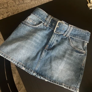 Blå jeanskjol med bälte från Pull&Bear - Säljer en blå jeanskjol från Pull&Bear med tillhörande bälte i midjan. Den är som ny då den är för liten för mig :)