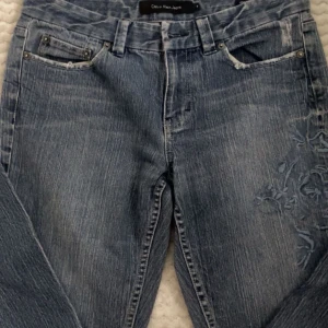 Blå jeans från Calvin Klein Jeans  - Säljer ett par vintage jeans som är low Rise flare från Calvin Klein Jeans med snygga broderade detaljer på ena benet. Köpt på second hand och används ett fåtal gånger. 