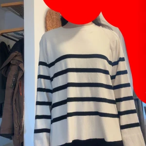 Vit och svart randig stickad tröja - Säljer en vit stickad tröja med svarta horisontella ränder. Tröjan har rund halsringning och långa ärmar. Perfekt för en avslappnad och stilren look.