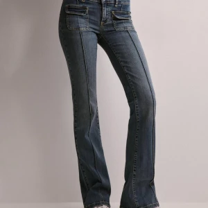 Blå bootcut jeans med låg midja - Snygga blå jeans med bootcut passform och låg midja från Nelly. Klassisk femficksmodell med markerade sömmar. Perfekta för en trendig vardagslook.