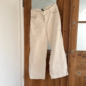 Vita manchesterbyxor från H&M Divided - Säljer ett par vita manchesterbyxor från H&M Divided i storlek 36. Byxorna har normal passform med raka, vida ben och klassisk femficksdesign. Stängs med dragkedja och knapp framtill. Perfekta för en stilren och trendig look.