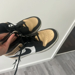 Nike Air Jordans i svart, vitt och guld - Säljer ett par Nike Air Jordans med svart, vitt och guld på ovandelen. Skorna har klassisk hög siluett, svart snörning och vit sula. Perfekta för dig som vill sticka ut med en unik färgkombination.pris går att diskutera 