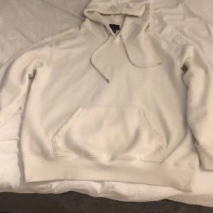 Vit hoodie från H&M - Säljer en vit hoodie från H&M i loose fit-modell. Tröjan har huva med dragsko och en stor magficka framtill. Perfekt för en avslappnad stil och enkel att matcha med det mesta.
