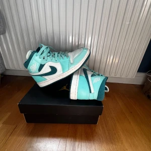 Turkosa Nike Air Jordans sneakers - Säljer ett par Nike Air Jordans i turkos och vitt med svart swoosh. Skorna har högt skaft, snörning och klassisk Air Jordan-logga på sidan. Perfekta för dig som vill sticka ut med färg på fötterna. Kommer med originalkartong.