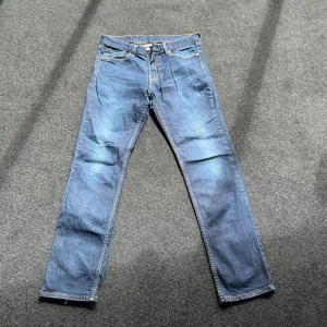 Levi's 511 blå jeans - Säljer ett par klassiska blå Levi's 511 jeans med normal passform och raka ben. Jeansen har fem fickor, dragkedja och knapp i midjan samt den ikoniska läderpatchen bak. Perfekta till vardags och lätta att matcha med det mesta.