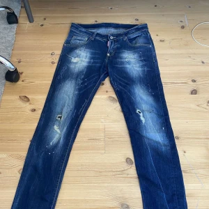  Dsquared2 jeans - Säljer ett par mörkblå jeans från Dsquared2 med slitningar och färgstänk på benen. Bra skick. Priset kan gå ner vid snabb affär!