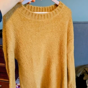 Gul stickad tröja från Benetton - Mysig gul stickad tröja från Undercolors of Benetton. Tröjan har en lös passform, rund halsringning och långa ärmar. Perfekt för lager-på-lager och enkel att styla till olika outfits.