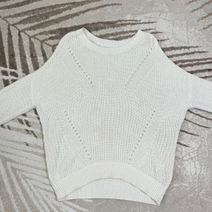 Vit stickad tröja med volangärmar - Superfin stickad tröja från Amisu i storlek M. Klassisk vit färg som passar perfekt till både vardag och lite finare tillfällen. Mjuk och bekväm kvalitet i 50 % bomull och 50 % akryl – värmande utan att kännas tung.  Det finns en liten fläck och visst slitage (se bild), men tröjan är i gott skick i övrigt.   