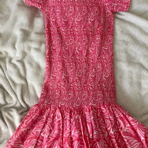 Rosa mönstrad kortklänning H&M - Supersöt rosa kortklänning från H&M med vitt mönster och smockad överdel. Klänningen har korta ärmar och volangig kjol, perfekt för varma dagar. Lätt och luftig känsla, passar dig som gillar färg och mönster.