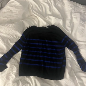 Randig svart och blå tröja från Zara - Svart långärmad tröja från Zara i storlek S med blå horisontella ränder. Tröjan har en klassisk rund halsringning och är tillverkad i ett mjukt, tunt material som passar perfekt för lager-på-lager-stil.