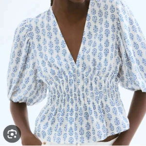 Blus - Supersöt blus från H&M i vitt med blått mönster, v-ringad och med bred smock i midjan. Puffiga trekvartsärmar ger en trendig siluett. Perfekt till jeans eller kjol för en fräsch look. Luftig och skön i bomull. Jag har aldirg använt den