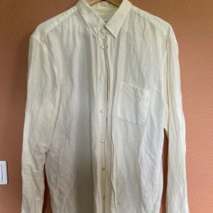 Vit linneskjorta från Our Legacy - Säljer en stilren vit skjorta från Our Legacy i luftig linne. Skjortan har klassisk krage, bröstficka och knäppning framtill. 