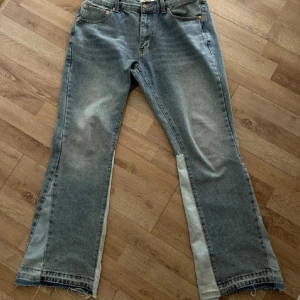 Gallery Dept Jeans - Unika ljusblå jeans från Gallery Dept. med bootcut-snitt och råa kanter nertill. Byxorna har kontrasterande ljusare paneler längs benen och klassisk femficksdesign. Tillverkade i kraftig denim med cool vintagekänsla och tydliga detaljer.