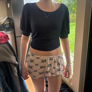 Svart croppad topp med puffärm - Snygg svart croppad topp med puffiga korta ärmar och rund halsringning. Toppens material känns mjukt och stretchigt, perfekt för en trendig och avslappnad look. Enkel att matcha med både jeans och kjol.