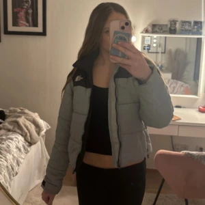 Grå pufferjacka från The North Face XS - Säljer en grå pufferjacka från The North Face i storlek XS. Jackan har svart axelparti, hög krage och dragkedja framtill. Den är vadderad och har en klassisk boxig passform som är riktigt trendig just nu.
