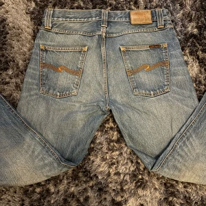 Nudie Jeans Steady Eddie  - Blå jeans från Nudie Jeans, modell Steady Eddie. Tillverkade i 100% ekologisk bomull med klassisk femficksdesign och snygga kontrastsömmar på bakfickorna. Rak passform och normal midja, perfekt för en avslappnad stil.