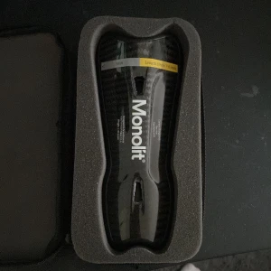 Monolit benskydd i kolfiber - Säljer ett par svarta Monolit benskydd i kolfiber, längd 19 cm. De är lätta och har en snygg glansig finish med Monolit-logga. Kommer i ett smidigt fodral. Perfekta för dig som vill ha riktigt schyssta och tåliga benskydd på planen. Helt nya, värde 789kr nya. Aldrig använda! 