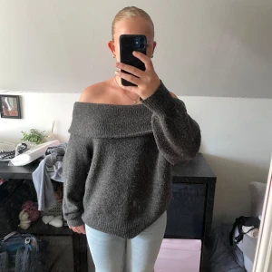 Mörkgrå offshoulder stickad tröja H&M - Mysig mörkgrå stickad tröja från H&M med bred offshoulder-ringning. Tröjan har lång ärm och en loose fit som ger en chill vibe. Perfekt att styla med jeans eller kjol för en trendig look.