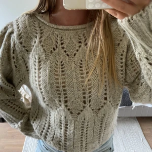 Beige stickad tröja med hålmönster - Superfin beige stickad tröja med snyggt hålmönster och rund hals. Tröjan har en lite loose passform och långa ärmar, perfekt att slänga på sig när det är kyligt. Den är mjuk och mysig, passar perfekt till jeans eller kjol.