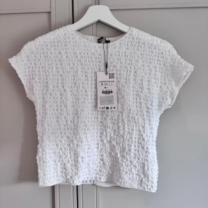 Vit strukturerad topp från Zara - Vit topp från Zara med korta ärmar och en cool, strukturerad yta. Helt ny med prislapp kvar.