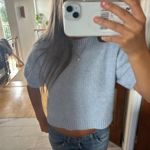 Ljusblå croppad stickad tröja - Superfin ljusblå stickad tröja med korta ärmar och croppad passform. Inga defekter.