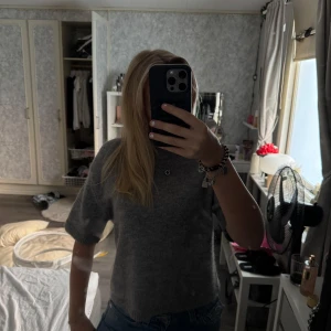 Grå stickad kortärmad tröja GinaTricot - Mysig grå stickad tröja från GinaTricot med korta ärmar och rund hals. Tröjan har en loose fit och är perfekt att styla med jeans eller kjol. Materialet är mjukt och ger en chill vibe, perfekt för lager-på-lager under hösten.