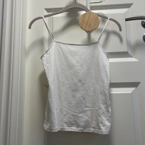 Vit linnetopp från Kappahl - Enkel och stilren vit linnetopp från Kappahl med tunna axelband. Linnet är gjord i mjuk bomull och har en rak passform som passar perfekt till jeans eller shorts. Perfekt för varma dagar och enkel att matcha med andra plagg, i storlek 158/164❤️