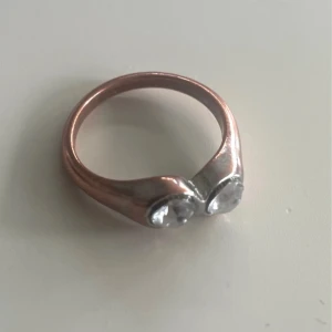 Vacker vintage ring ”Toi et Moi” - En charmig vintagering i stilen ”Toi et Moi” (du och jag) som har fått sitt namn av de två stenarna som samsas på dess framsida. De två stenarna symboliserar tvåsamhet och partnerskap. Stenarna är fasettslipade kristaller med en vacker lyster.  Den har en varm och lugnande kopparfärg som kommer av bruksslitage men har gett ringen ett unikt utseende . Strl 17,7