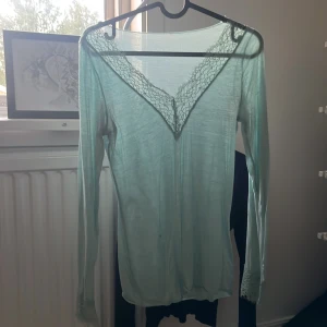 Intimissimi tröja - Säljer en ljusgrön långärmad topp med v-ringning och fina spetsdetaljer både vid halsringningen och ärmsluten. Tunt och lätt material. 