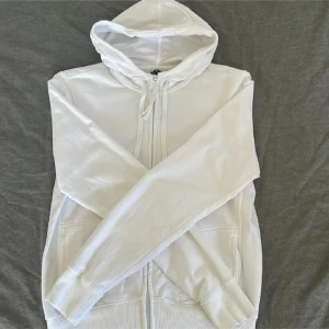 Vit hoodie  - Klassisk vit hoodie med dragkedja framtill och huva med snörning. Är i storlek Xl men sitter som en S.
