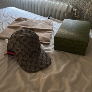 Gucci keps med GG-mönster och röd/blå  - Snygg keps från Gucci i beige/blå med klassiskt GG-monogram över hela kepsen. Använts fåtal gånger säljer pga bytt stil