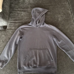 Grå hoodie från Weekday XS - Säljer en stilren grå hoodie från Weekday i storlek XS. Tröjan har klassisk huva med snörning, magficka och ribbade muddar. Perfekt för dig som gillar en enkel och clean look. Materialet är mjukt och skönt, passar året runt.