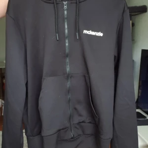 Svart hoodie med dragkedja från McKenzie - Svart hoodie från McKenzie med hel dragkedja framtill, huva med snörning. Använd fåtal gånger