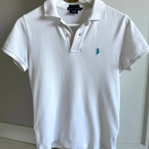 Ralph Lauren Piké - Jättesnygg Piké tröja från Ralph lauren, tröjan är vit och har en ljusblå logga. Passar perfekt till sommaren. Passar till allt men bäst till linnebyxor. Jag är 170cm lång och den är lite för liten, kontakta mig för frågor eller om du vill sänka pris!