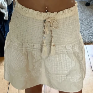 Beige kortkjol brodering Zara - Supersöt beige kortkjol från Zara med smockad midja. Perfekt för sommaren!💕Nypris: 400kr