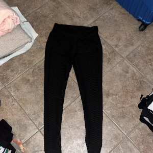 Svarta scrunch-leggings från SHEIN - Svarta leggings från SHEIN i storlek S med scrunch-detalj bak och coolt strukturerat tyg. Hög midja och tight passform som framhäver formerna. Perfekta för gymmet eller chill dagar. Superstretchigt material som sitter skönt hela dagen.