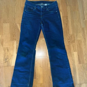 Blå bootcut jeans från &Denim - Säljer ett par klassiska blå bootcut jeans från &Denim. Byxorna har låg midja och femficksmodell med snygga kontrastsömmar. Perfekta för dig som gillar en tidlös jeansstil med lite utsvängda ben.
