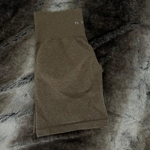 Bruna seamless shorts från NVGTN - Snygga bruna seamless shorts från NVGTN med hög midja och tight passform. Perfekta för gymmet eller andra träningspass. Mjukt och stretchigt material som sitter skönt och formar sig efter kroppen. Diskret logga framtill i midjan.