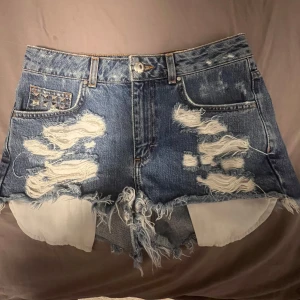 Supersnygga jeansshorts med nitar - Säljer ett lag nya jeansshorts från bikboks super gamla vintage kollektion. De har nitat både fram och bad och slitningar som dekor. Köpta 2016 och finns ej kvar längre. Super bra skick och super snygga. Nypris ca 500kr.