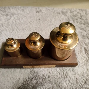 Sats med mässingsvikter från Skultuna - Skultuna  - En klassisk uppsättning mässingsvikter i olika storlekar, perfekt för dig som gillar fysik, teknik eller samlar på vintageprylar. Snyggt placerade på en träbricka – både dekorativt och användbart för experiment eller inredning.