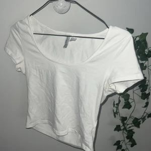 Vit croppad t-shirt - Säljer en enkel vit croppad t-shirt.              T-shirten har korta ärmar och rund halsringning. Perfekt till sommaren och lätt att matcha med olika outfits.
