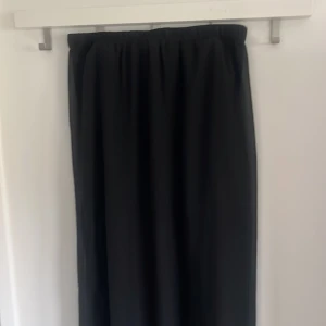 Svart långkjol från Divided - Säljer en svart långkjol från Divided med resår i midjan. Kjolen har en luftig och flowy känsla, perfekt för dig som gillar en enkel och stilren look. Passar till många olika outfits och är lätt att matcha.