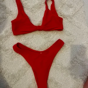 Röd bikini - Snygg röd bikini med ribbad struktur och breda axelband från Nelly. Ej vadderad. Storlek 38.